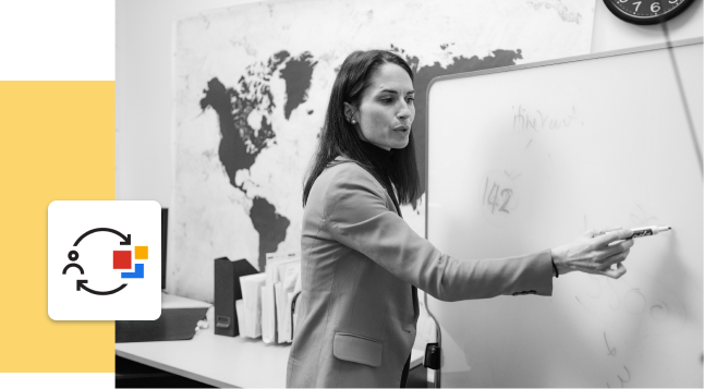 photo en noir et blanc d'une personne pointant un tableau blanc, avec un graphique jaune sur le côté gauche
